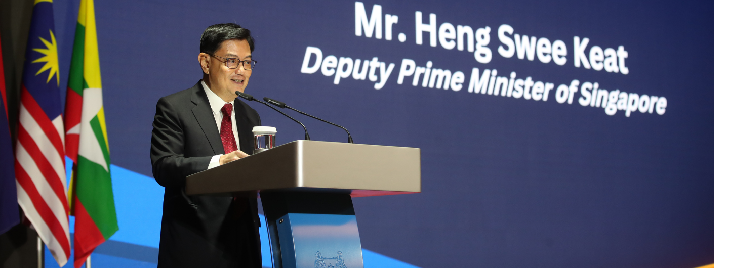 Mr. Heng Swee Keat speaks at a podium, with flags in the background.